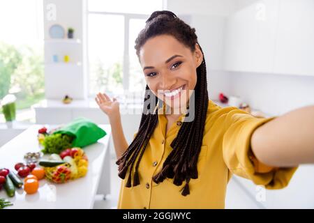 Foto von süßen liebenswert dunkle Haut Frau gekleidet gelben Hemd Zöpfe laden Sie Kochen Frühstück lächelnd im Haus Heim Zimmer Stockfoto