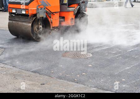 Straßenreparatur, Verdichter legt Asphalt. Reparieren Sie Pflaster und legen Sie neue Asphalt Patching-Methode im Freien. Stockfoto