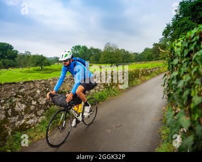 Road Bike Tour mit Gepäck, Bikepacking auf einer einsamen Küstenstraße in Asturien, Nordspanien Stockfoto