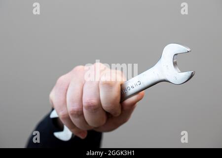 Ein Porträt einer Hand einer Person oder eines Bauarbeiters mit einem Metallschraubenwerkzeug aus Chrom mit offenem Ende. Stockfoto