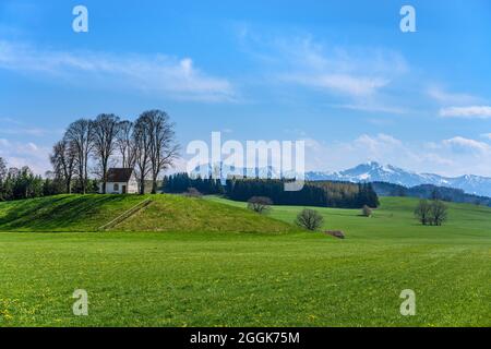 Deutschland, Bayern, Oberbayern, Pfaffenwinkel, Antdorf, Frühlingslandschaft mit Kirnberger Kapelle vor den Ausläufern der Alpen mit Herzogstand und Heimgarten Stockfoto