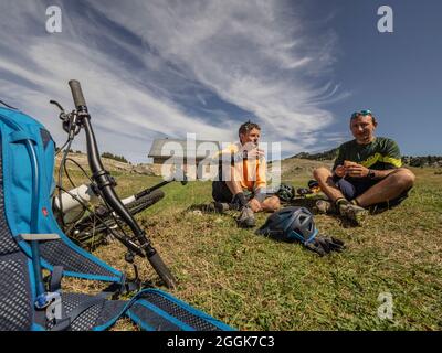 Mountainbiker ruhen sich bei einer Hütte in Cabane de Pré-Peyret auf einer Tour durch das Naturschutzgebiet Hauts-Plateaus du Vercors im Departement Auvergne-Rhône-Alpes aus. Stockfoto