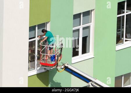 Nischni Nowgorod, Russland, Gagarin Avenue 101 b, Schule Nr. 34. 08.26.2021. Eine Frau, Angestellte einer Reinigungsfirma, wäscht die Fenster des Gebäudes Stockfoto