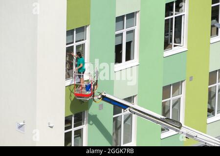 Nischni Nowgorod, Russland, Gagarin Avenue 101 b, Schule Nr. 34. 08.26.2021. Eine Frau, Angestellte einer Reinigungsfirma, wäscht die Fenster des Gebäudes Stockfoto