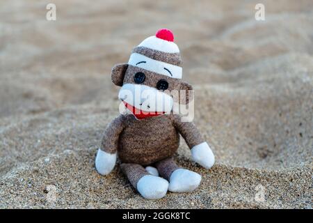 Nahaufnahme eines beigen gehäkelten Affen auf dem Sand Stockfoto
