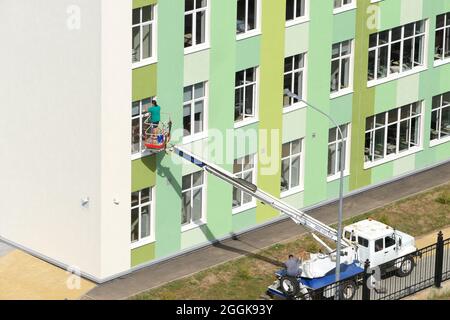 Nischni Nowgorod, Russland, Gagarin Avenue 101 b, Schule Nr. 34. 08.26.2021. Eine Frau, Angestellte einer Reinigungsfirma, wäscht die Fenster des Gebäudes Stockfoto