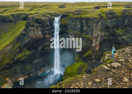 Luftaufnahme einer Frau mit Rucksack, die den Haifoss-Wasserfall des Island Highlands genießt Stockfoto