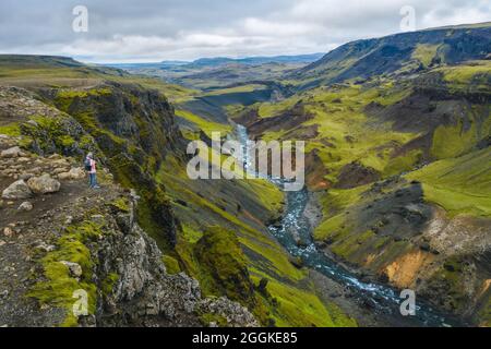 Luftaufnahme einer Frau mit Rucksack, die das isländische Hochland und den Fluss Fossa in der Nähe des Haifoss Wasserfalls in Island genießt Stockfoto