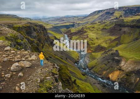 Luftaufnahme des Menschen, der die isländische Landschaft mit Hochlandtal und Fluss Fossa mit blauem Wasserbach und grünen Hügeln und moosbedeckten Klippen genießt. Stockfoto