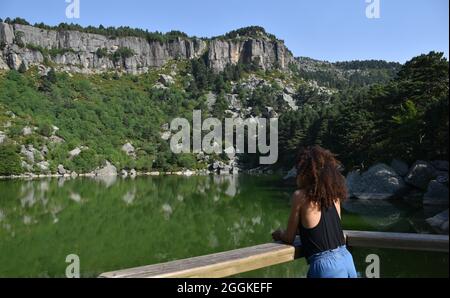 Rassialisierte Frau mit Afro-Haaren, die aus der Sicht die Schönheit der Schwarzen Lagune beobachtet. Das Hotel liegt in der Provinz Soria, Spanien. Stockfoto