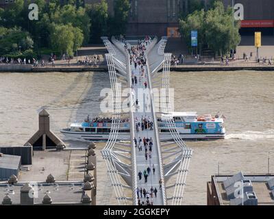 London, Greater London, England, August 24 2021: Luftaufnahme der Millennium Bridge auf der Themse, während ein Boot unter der Brücke vorbeifährt. Stockfoto