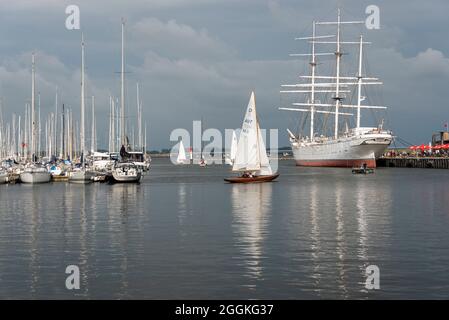 Deutschland, Mecklenburg-Vorpommern, Stralsund, Segelboote fahren vom Stadthafen Stralsund zum Strelasund, auf der rechten Seite ist die Gorch Fock 1 im Hafen. Stockfoto