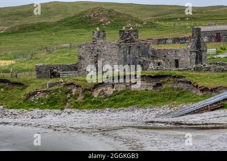 Zerstörtes Gebäude hinter dem Strand von Gossabrough am Wick of Gossabrough an der Ostküste von Yell, Shetland. Stockfoto