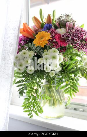 Ein farbenfroher Strauß steht in einem Fenster Stockfoto