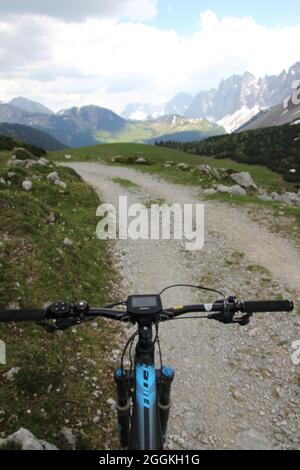 E-Bike neben alpiner Blumenwiese, Lenker mit Display, weiß silberner Arum (Dryas octopetala), Abfahrt vom Karwendelhaus zum kleinen Ahornboden. Laliderer Wände vor der Falkenhütte Stockfoto