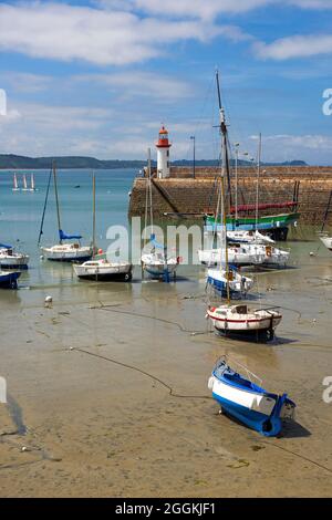 Ebbe im Hafen von Erquy liegen Boote im Sand, im Hintergrund der kleine Leuchtturm am Pier, Frankreich, Bretagne, Côtes d´Armor, Côte de Penthièvre Stockfoto