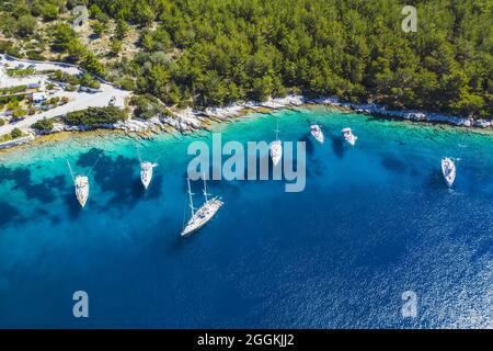 Luftbild von Segelbooten, die in der blauen Bucht von Fiskardo, Insel Kefalonia, Ionisches, Griechenland angedockt sind Stockfoto