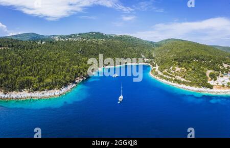 Panoramablick auf den Foki Beach und Segelyachten, die in einer türkisfarbenen Bucht festgemacht sind. Fiskardo, Insel Kefalonia, Griechenland, Stockfoto