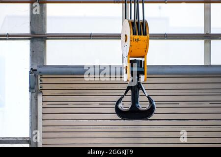 Uebach-Palenberg, Nordrhein-Westfalen, Deutschland - Kranhaken am Portalkran vor einer Rollentür in einer Industriehalle des Maschinenwerks NEA. Stockfoto