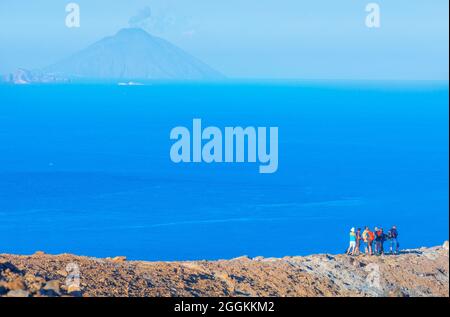 Menschen, die den Blick auf die Insel Stromboli vom Gran Cratere-Rand, der Vulcano-Insel, den Äolischen Inseln, Sizilien, Italien genießen Stockfoto
