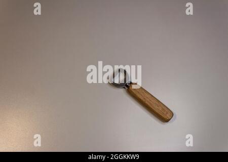 Flaschenöffner. Flaschenöffner auf weißem Hintergrund. Flaschenöffner aus Holz und Stahl auf einem weißen Tisch Stockfoto