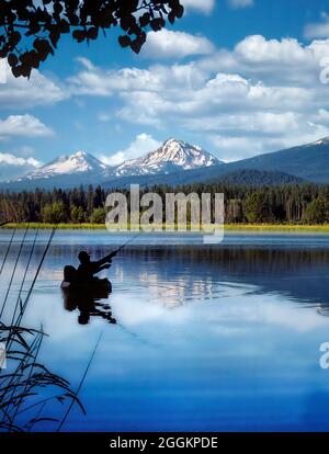 Float Tube Fly Fisherman auf Black Butte Teich mit Three Sisters Mountains. Oregon. Stockfoto