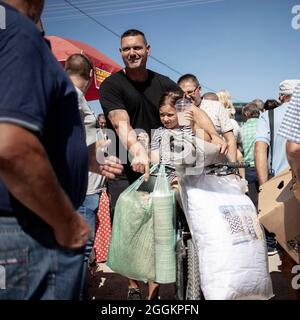 Sokobanja, Serbien, 19. Aug 2021: Ein Mann aus der Stadt, der mit einem kleinen Mädchen und einem Haufen von Sachen, die auf einem Dorfmarkt gekauft wurden, ein Fahrrad schiebt Stockfoto