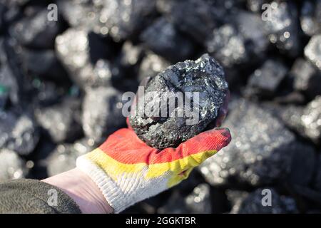 Ein Stück Kohle in der Hand eines Mannes. Fossile Brennstoffe für die Heizzeut. Stockfoto