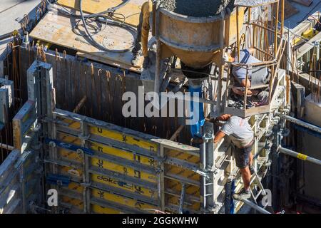 Wien, Betonarbeiten auf der Baustelle, Arbeiter, Betonieren einer Elementwand mit Betoneimer und Fallrohr im Jahr 22. Donaustadt, Wien, Österreich Stockfoto