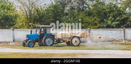 Traktor sprüht Gras mit Dünger auf dem Bauernhof, der Landwirtschaft und der ländlichen Landwirtschaft. Stockfoto