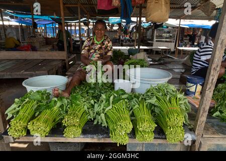 Sorong, Indonesien - 3. Oktober 2019: Eine ältere Frau verkauft an ihrem Imbissstand auf einem lokalen Markt in Sorong, West Papua, einige Brocken Mangold Stockfoto