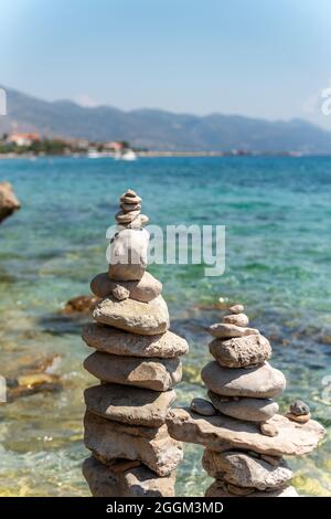 Pyramidensteine balancieren am Strand auf dem Hintergrund von blauem Meer und Himmel. Nahaufnahme. Stockfoto