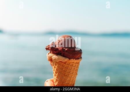 Leckeres Eis in der Hand auf dem Hintergrund das türkisfarbene Meer. Stockfoto