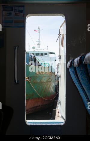 Sorong, Indonesien - 3. Oktober 2019: Blick von innen auf eine Fähre, durch eine offene Tür, auf ein rostig altes Schiff, das im Hafen von Sorong, West Papua, angedockt ist Stockfoto