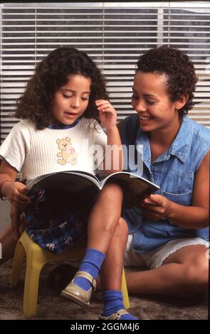 Austin Texas USA, 1996: Junge alleinerziehende hispanische Mutter (20), die mit einer vierjährigen Tochter liest. HERR ET-0264, 0265 ©Bob Daemmrich Stockfoto