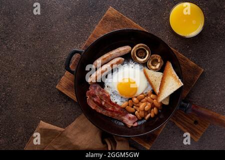 Traditionelles englisches Frühstück mit gegrillten Würstchen, Spiegeleiern, Speck, Pilzen, Toast und Bohnen Stockfoto