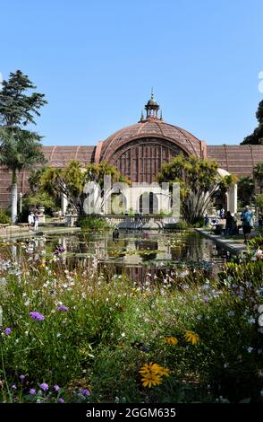 SAN DIEGO, KALIFORNIEN - 25 AUG 2021: Das Botanische Gebäude im Balboa Park mit Blumen und Lily Pond im Vordergrund. Stockfoto