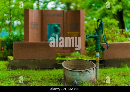 Handpumpe auf einem öffentlichen Friedhof vor einem großen Grab, selektive Schärfe, schönes Bokeh Stockfoto