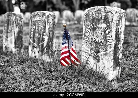 Farblich mit Graustufenfoto einer kleinen amerikanischen Flagge, die die Gräber von Todesopfern auf dem Antietam National Cemetery in Sharpesburg, Maryland, markiert. Stockfoto