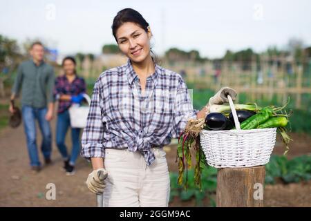 Lächelnde asiatische Frau hält Gemüse im heimischen Garten angebaut Stockfoto