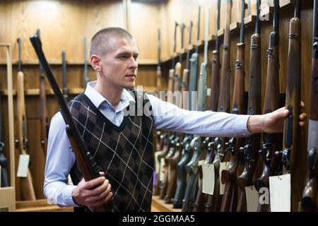 Porträt des Kunden, der Kampf Gewehrgewehr in Armee-Markt zu wählen. Stockfoto