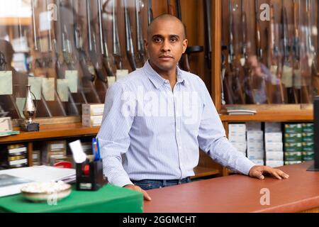 Porträt des Besitzers eines Waffenladens vor dem Schaufenster mit Jagdgewehren Stockfoto