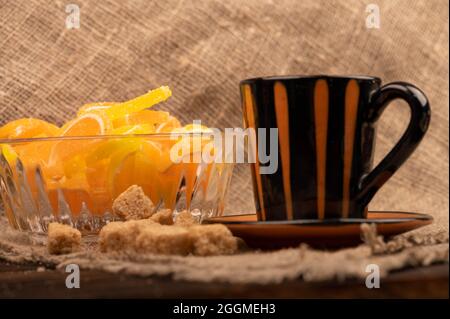 Bunte, geformte Marmeladenscheiben in einer Glasvase, Stücke braunen Rohrzuckers und eine Tasse Kaffee, Nahaufnahme, selektiver Fokus Stockfoto