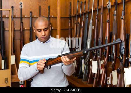 Porträt eines Mannes in der Waffenhandlung mit Gewehr Stockfoto