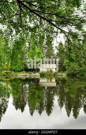 Vertikale Aufnahme einer Lodge, die auf der Seite eines von Bäumen umgebenen Sees steht Stockfoto