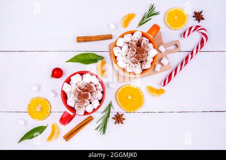 Weihnachtliche Kulisse mit zwei Tassen Kakao und Marschmalchen, Mandarinen-Keilen, frischen Rosmarinzweigen und festlichem Dekor Stockfoto