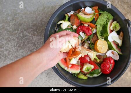 Hausmüll für Kompost von Obst und Gemüse. Frau wirft Müll. Stockfoto