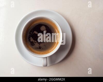 Keramikbecher mit Heißgetränk, schwarzer Kaffee auf Holztisch. Einfache Zusammensetzung mit einer Tasse Kaffee. Morgenstimmung. Stockfoto