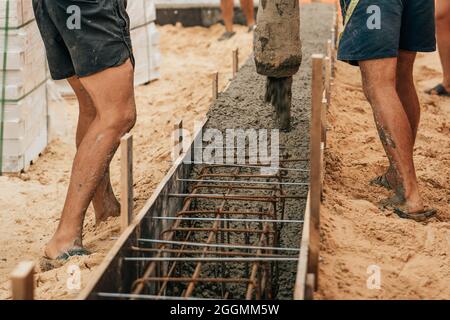 Bau des Gebäudefundaments. Ausgießen mit flüssigem Beton aus Schalung mit Stahlblech. Baustelle, Entwicklungskonzept. Stockfoto