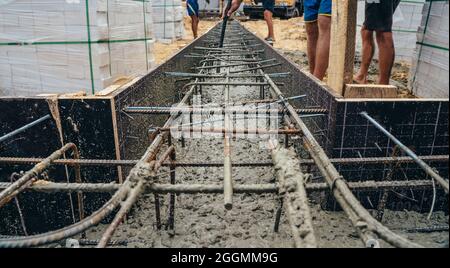 Gießen von Zement oder Beton mit automatischer Pumpe, Baustelle mit verstärktem Gitter-Fundament, Beginn des neuen Hausbaus. Stockfoto